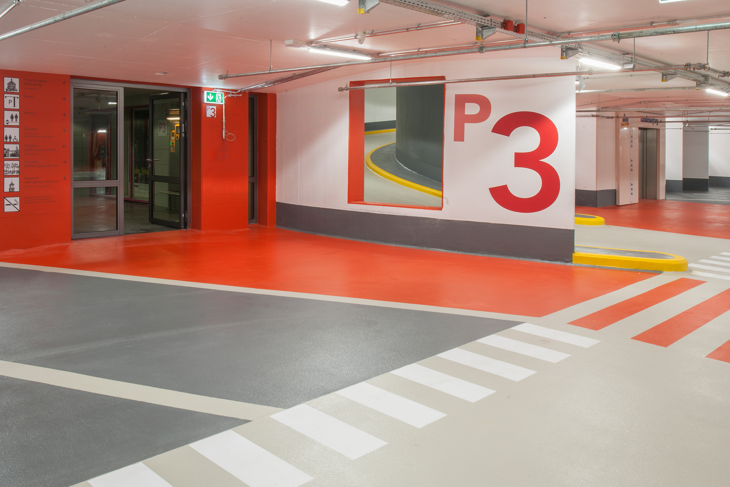 Entré till trapphus med röd gångbana och mörkgrå parkeringsfickor på plan 3