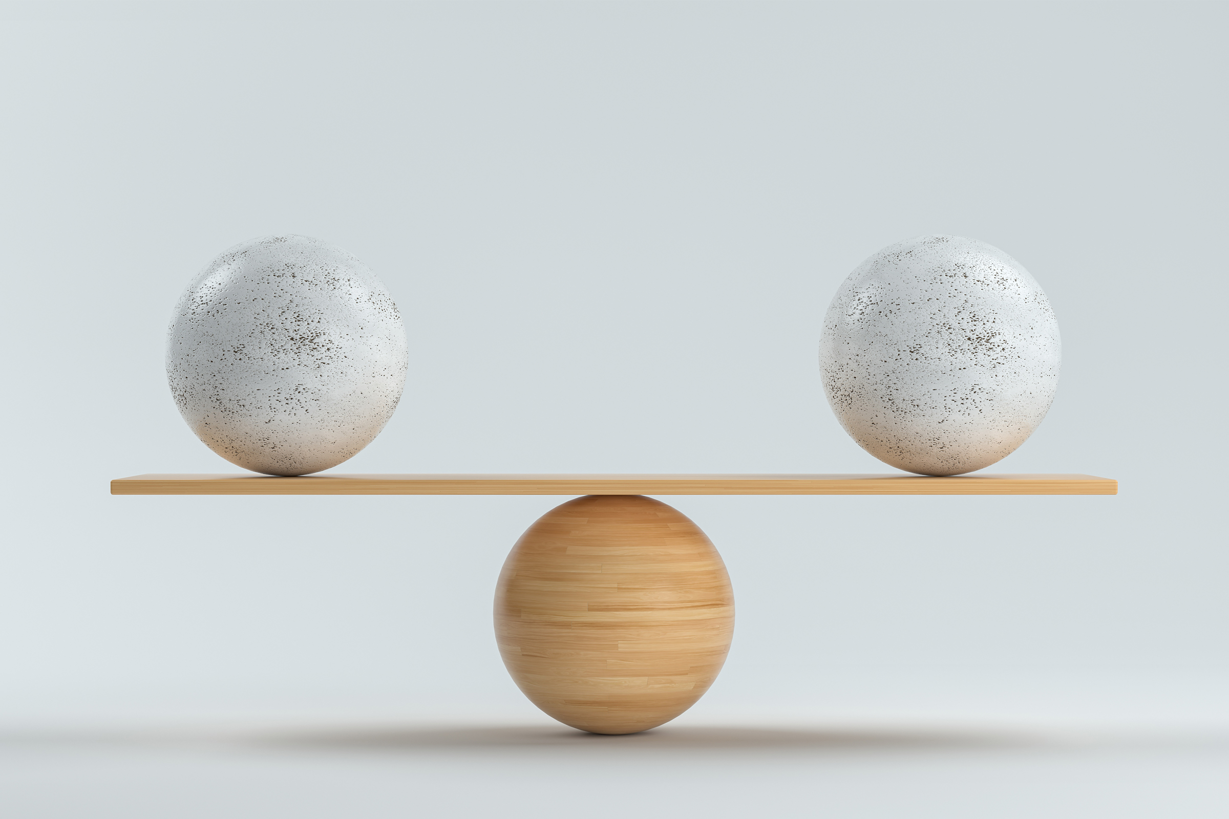 En balansbräda av trä som balanserar två lika stora bollar av sten.