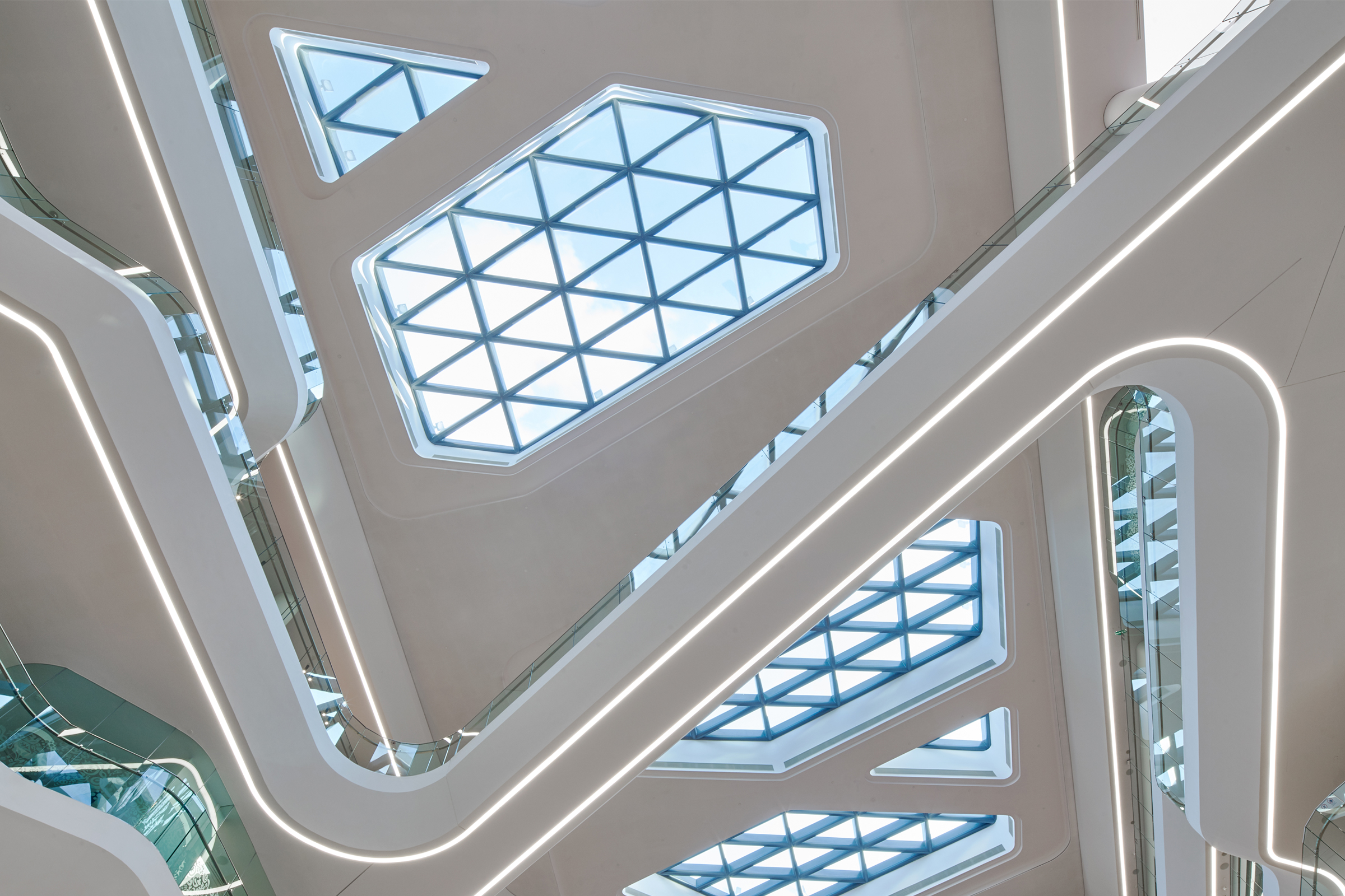 Akustiktak med vita ljussatta moduler och glastak.