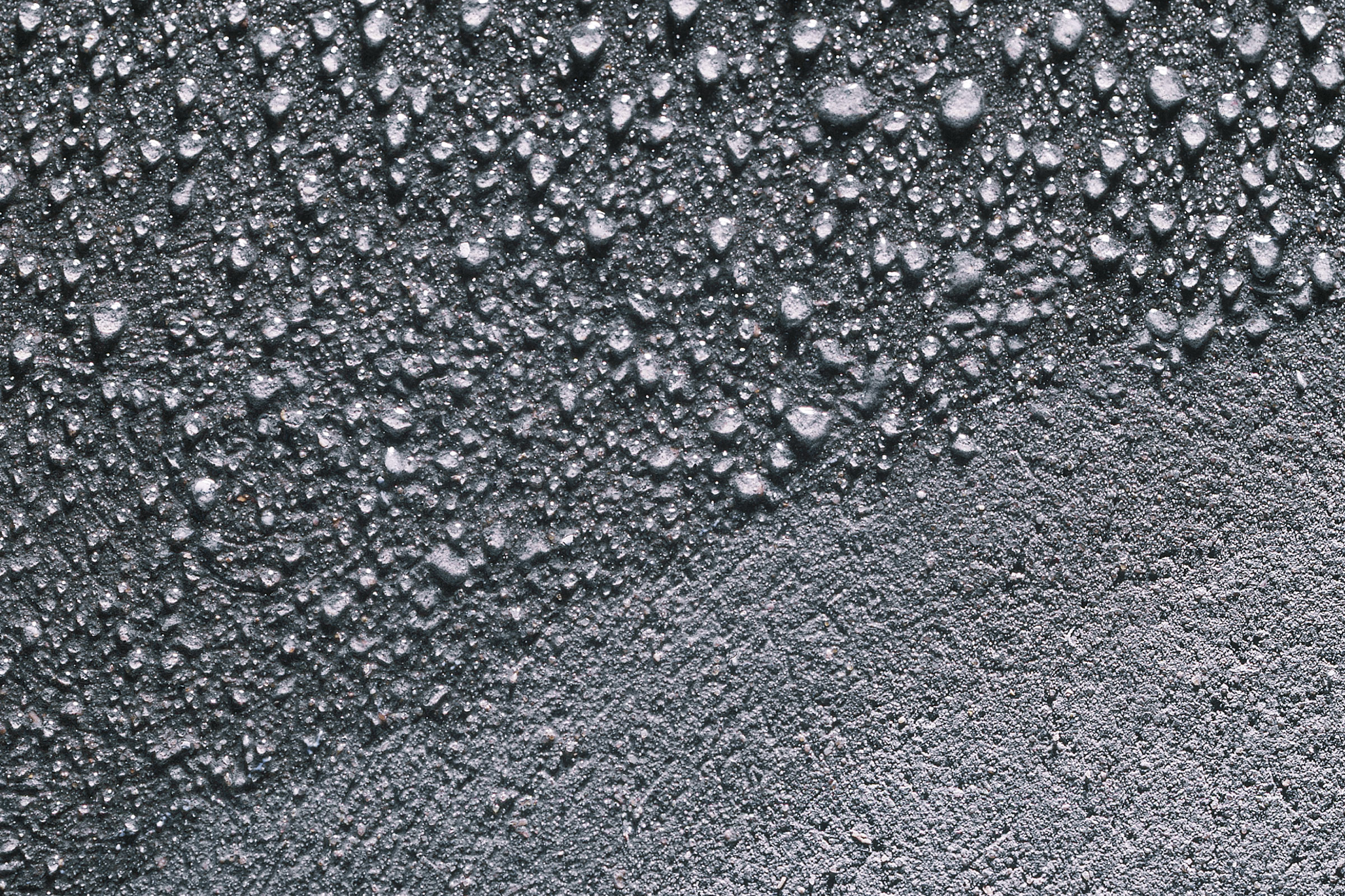 En betongyta med vattendroppar på den del av betongen som inte blivit impregnerad.