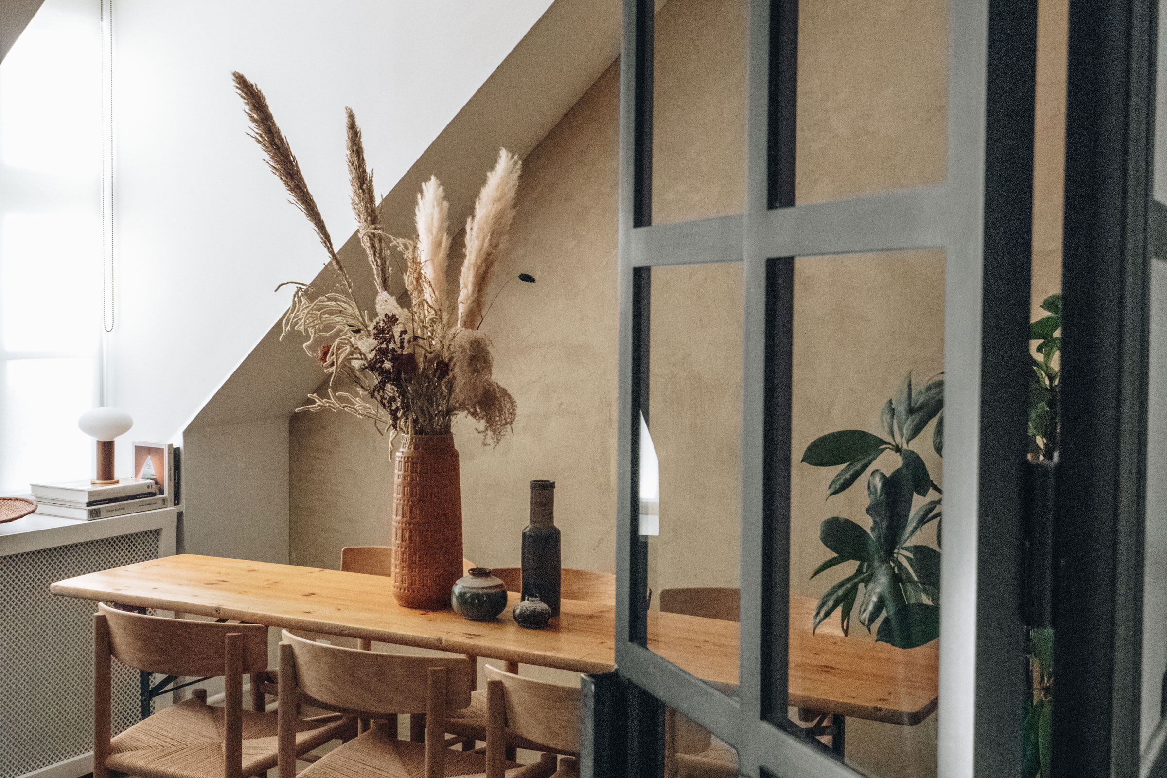 Beiga kalkväggar och matbord med en vas på bordet