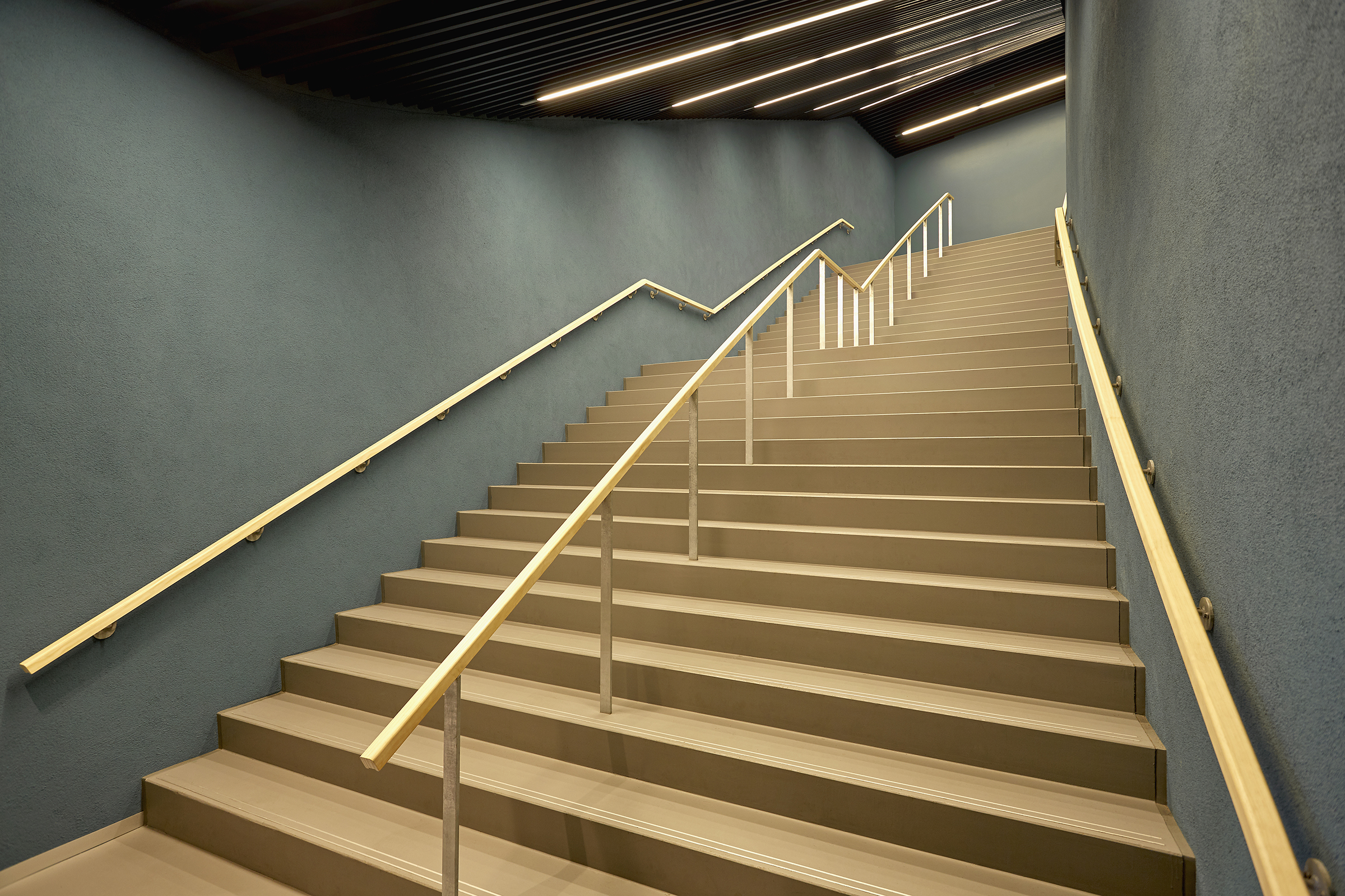 Trapphus med gröna väggar och trappor i ljust trä.